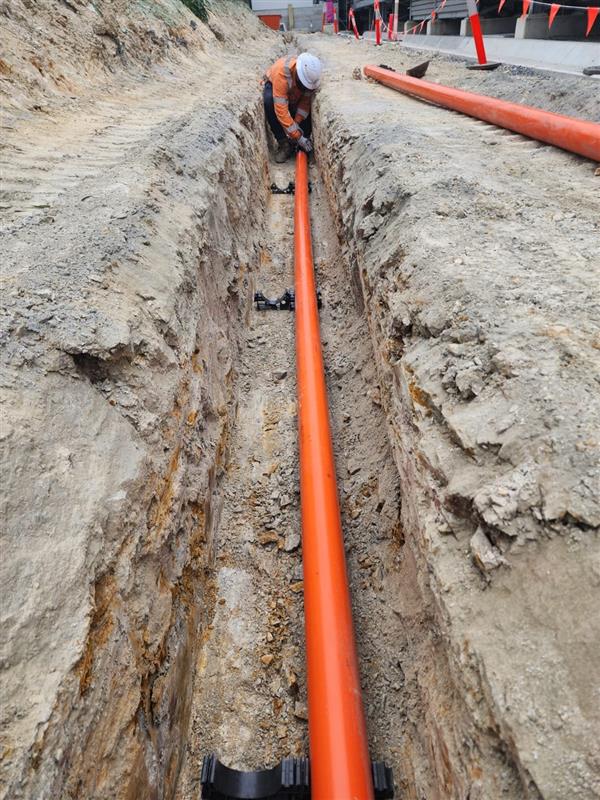 Civil construction crews completing rail drainage works beside railway infrastructure.