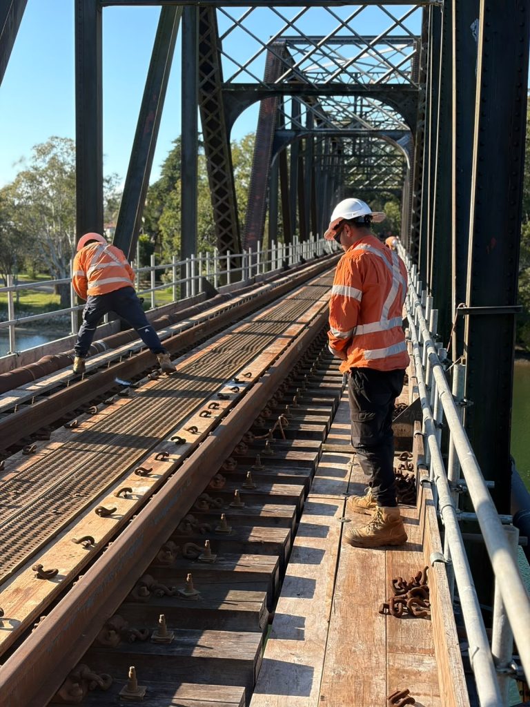 Track worker checking a rail fastening during preventative railway maintenance
