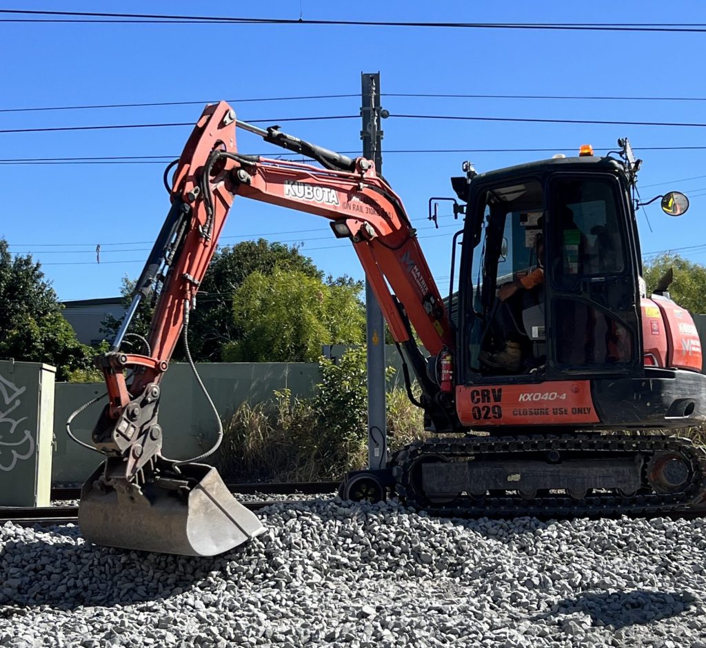 Rail excavator supporting ballast maintenance beside railway track