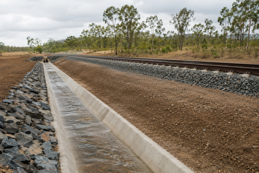 Constructed drainage channel carrying stormwater beside a rail corridor